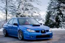 Синий Subaru Impreza на парковке близ зимнего леса